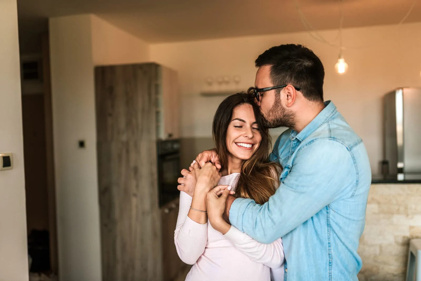 Pareja joven abrazada en la cocina de su casa